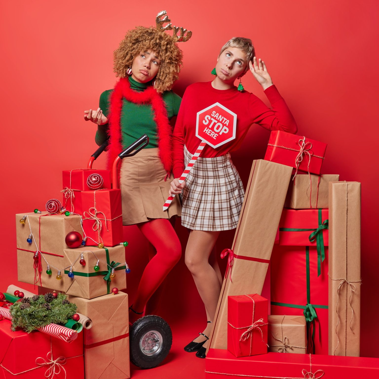 Thoughtful displeased women being busy decorating house before New Year wear festive clothes pose